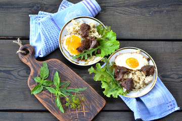 Fried eggs with bacon in a pan seasoned with herbs and pepper, flat lay image
