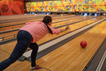 Fototapeta na wymiar Young woman playing bowling in club. Adult lady spending time enjoying weekend and playing in sport game.