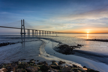 Fototapeta na wymiar Vasco da Gama Bridge and pier over Tagus River in Lisbon, Portugal, at sunrise.