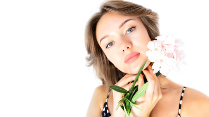 Young beautiful female woman with make-up, plump lips, clean skin and flowers isolated on white background. Pure fresh skin, lip plumping concept. Copy space.