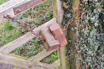 Old wooden gate held shut with metal weights