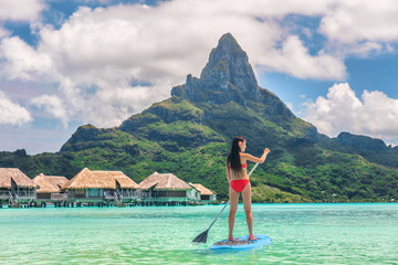 Tahiti Bora Bora island vacation recreational activity watersport woman paddleboarding on SUP Stand Up Paddle Board at luxury resort hotel in French Polynesia. Mt Otemanu summer holiday landscape. - obrazy, fototapety, plakaty