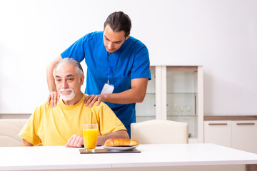Young male doctor visiting old patient at home