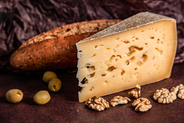 Cheese, bread and nuts on a dark background