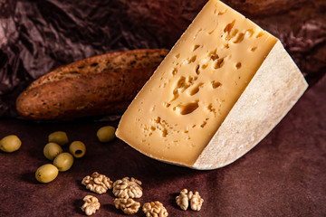 Cheese, bread and nuts on a dark background