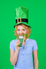 Beautiful girl in green leprechaun hat drinking green beer. Woman celebrating St Patrick's Day with...