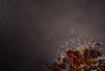 Star anise, pepper, salt on a black stone background. Top view with space for text.