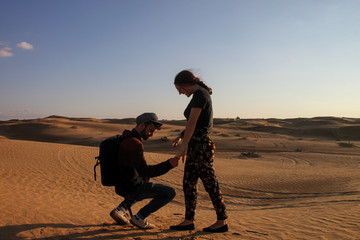 Young hipster couple enjoying the sunset in the desert