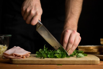 Person chopping fresh parsley visible chef hands and knife