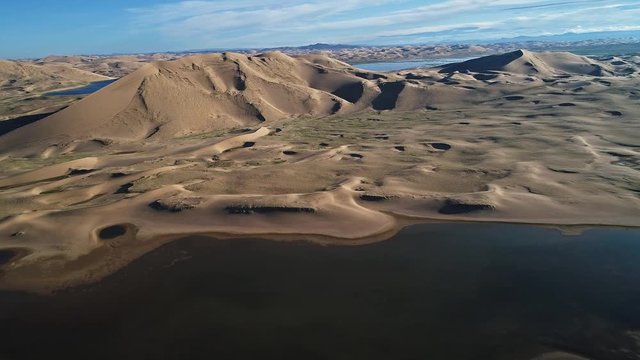 A large lake on the edge of a sandy desert. Mongolia sandy dune desert Mongol Els near lake Durgen Nuur. Khovd province, Western Mongolia.