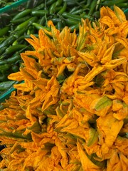 Exotic market display with squash flowers and green chili peppers