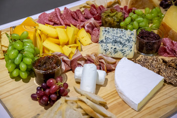 cheese and cold meat board with grapes and bread