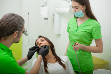 The dentist man are treating teeth to client in dental office