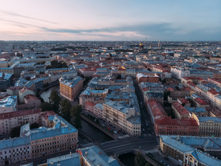Obraz premium Aerial view of red and grey rooftops of Saint Petersburg. On the background St. Isaac's Cathedral and Peter and Paul Cathedral. View from above on Moyka river. Evening light.
