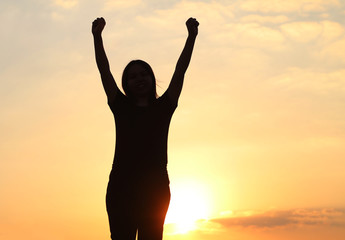 Fototapeta premium woman silhouette arms up to the sunset feeling happy and freedom.