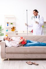 Young male doctor visiting old patient at home