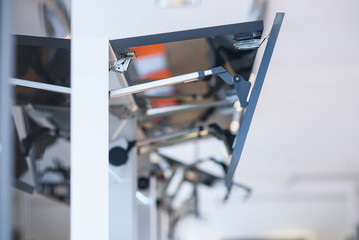 Kitchen cabinet with opened fronts with dish holder shelves inside. Lift system for bi-fold fronts for direct access in kitchen cabinets.