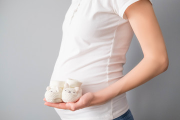 Pregnant woman holding small shoes for the unborn baby
