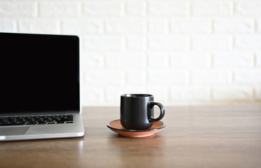 Black coffee cup and laptop on the desk in the office,copy space
