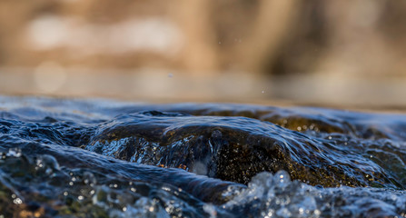 close up flowing water with brown background at local lake 