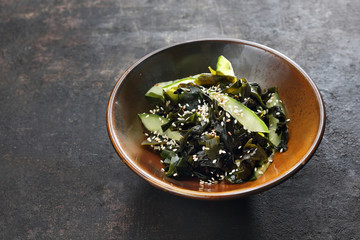 Fototapeta na wymiar Sunomono. Cucumber and wakame seaweed salad on dark background