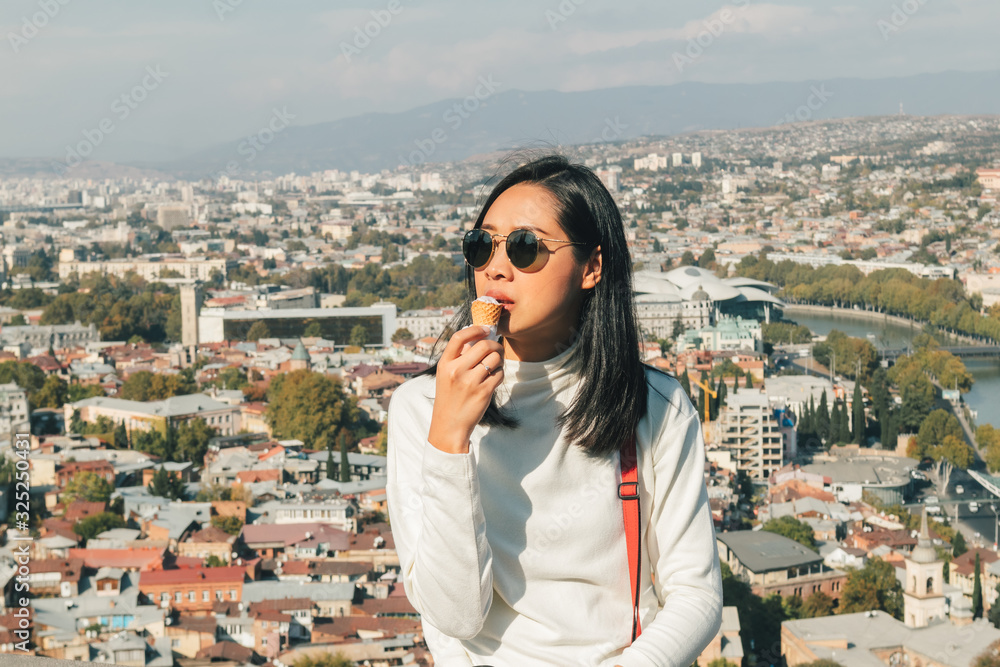 Wall mural asian woman tourist is taking selfie of herself with landscape view of tbilisi, georgia.