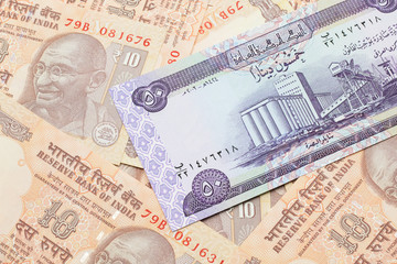 A purple Iraqi fifty dinar bank note close up in macro with an assortment of Indian ten rupee bank notes 