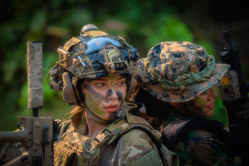 Two female soldiers are sitting with their backs and relax after fighting. War, soldier army, gun...