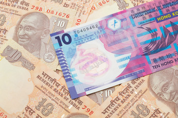 A close up image of a colorful Hong Kong ten dollar bill in macro on a bed of Indian ten rupee bank notes