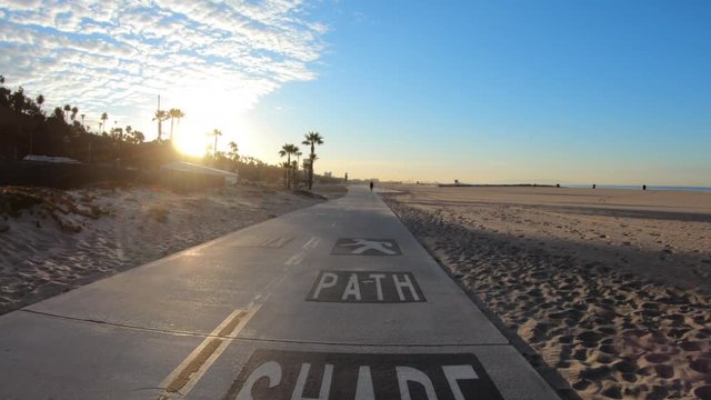 Santa Monica beach bike path share pavement sign with slow motion movement toward sunrise in scenic Los Angeles County California.