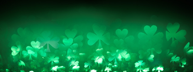 Green St Patricks day background with sparkling shamrock shapes