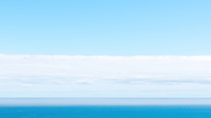 Fototapeta na wymiar Long view of Pacific ocean horizon with white clouds