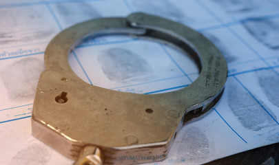 Fraud concept.Police Handcuffs on fingerprints crime page file.