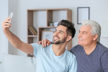 Obraz premium Young man and his father taking selfie at home