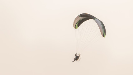 A paramotor gliding with people flying in the sky beautifully