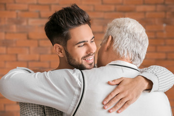 Young man and his father hugging at home