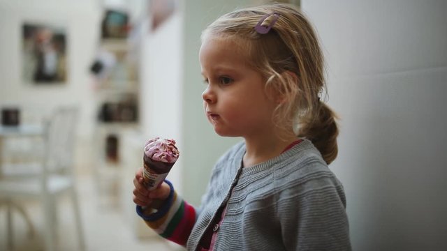 Cute small girl eat ice cream in the museum or library white wall
