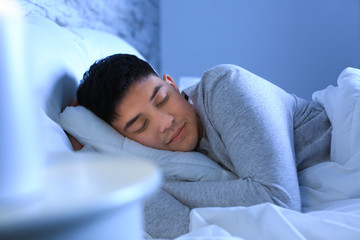 Asian man sleeping in bed at night