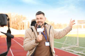 Male reporter with microphone at the stadium - obrazy, fototapety, plakaty