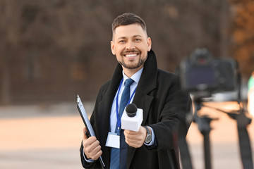 Male journalist with microphone outdoors