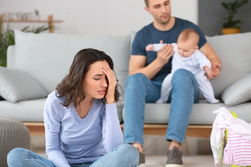 Father with his baby and wife suffering from postnatal depression at home