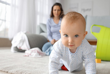 Cute baby and young woman suffering from postnatal depression at home