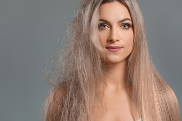 Beautiful young woman before and after hair treatment on grey background