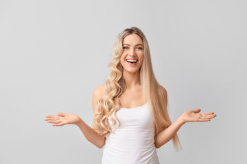 Beautiful young woman with curly and straight hair on light background