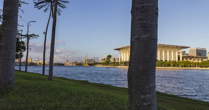 Phenomenal sunset at the Putrajaya lake with view over the skyline of Putrajaya. Time lapse between trees on a peaceful lake in Malaysia. Captured in a small palm tree forest on the shoreline.