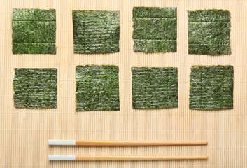 Tasty seaweed sheets and chopsticks on bamboo mat