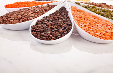 Bowls of various lentils in the shape of flower on a marble background.