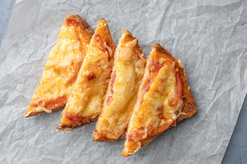 Sandwiches cooked in the oven with tomato and cheese on a paper. View from above.