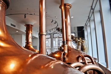 Copper brew kettle and spiral stairs filled with burlap bags of malt. Equipment for beer making in the traditional German way. 