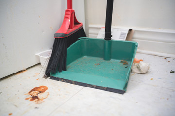 cleaning floor with dust pan and broom